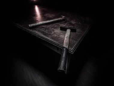 Koyu tonlu sisli bir arka planda, ahşap bir masanın üzerinde eski model bir çekiç. Seçici odak.