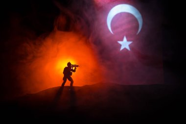 Türk ordusu konsepti. Türk bayrağına karşı silahlı asker silueti. Yaratıcı sanat dekorasyonu. Askeri siluetler dövüş sahnesinde sisli bir arka planda. Seçici odak