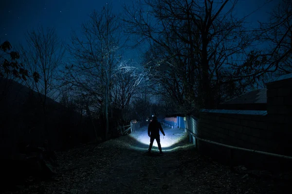 Full moon over quiet village at night. Beautiful night landscape of mountain village under the moonlight. Silhouette of person standing in the dark. Selective focus. Long exposure shot