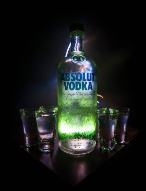 BAKU, AZERBAIJAN - FEB 09, 2020: Absolut Vodka is a brand of vodka, produced near Ahus, in Sweden. Owned by French group Pernod Ricard. Bottle of vodka on wooden table with dark toned foggy background.