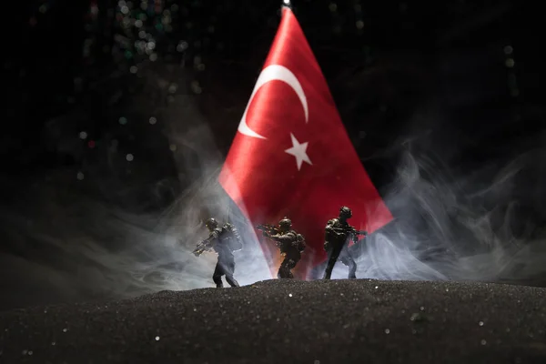 Turkish army concept. Silhouette of armed soldiers against a Turkish flag. Creative artwork decoration. Military silhouettes fighting scene dark toned foggy background. Selective focus