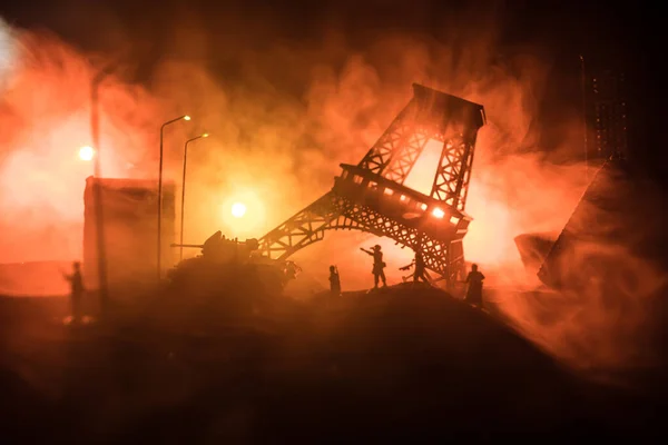 Empty street of burnt up city, flames on the ground and blasts with smoke in the distance. Apocalyptic view of city downtown as disaster film poster concept. Night scene. City destroyed by war.