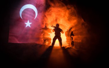 Türk ordusu konsepti. Türk bayrağına karşı silahlı askerlerin silueti. Yaratıcı sanat dekorasyonu. Askeri siluetler dövüş sahnesinde sisli bir arka planda. Seçici odak