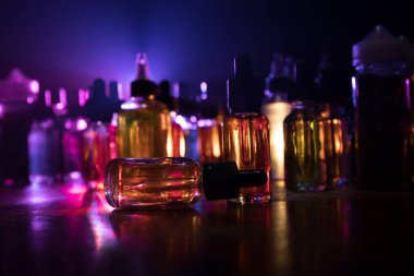 Vape konsepti. Karanlık arka planda duman bulutları ve tüp sıvısı şişeleri. Işık efektleri. Arka plan, vape reklamı ya da vape arkaplan olarak kullanışlı. Seçici odak