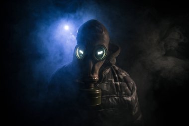 Çevre felaketi. Karanlık bir arka planda gaz maskeli kıyamet sonrası hayatta kalan biri. Gaz maskesi takan bir adamın dramatik portresi. Radyasyon koruması demek. Seçici odak