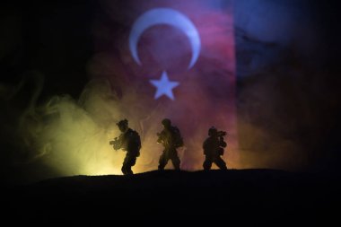 Türk ordusu konsepti. Türk bayrağına karşı silahlı askerlerin silueti. Yaratıcı sanat dekorasyonu. Askeri siluetler dövüş sahnesinde sisli bir arka planda. Seçici odak