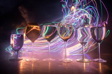 Ahşap masada şarap kadehi ve arka planda güzel renkli ışıklar. Karanlık arka planda şarap kadehleri. Seçici odaklanma. Kulüp içki konsepti