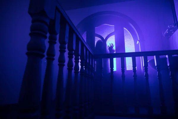 Inside of old creepy abandoned mansion. Silhouette of horror ghost standing on castle stairs to the basement. Horror Halloween concept