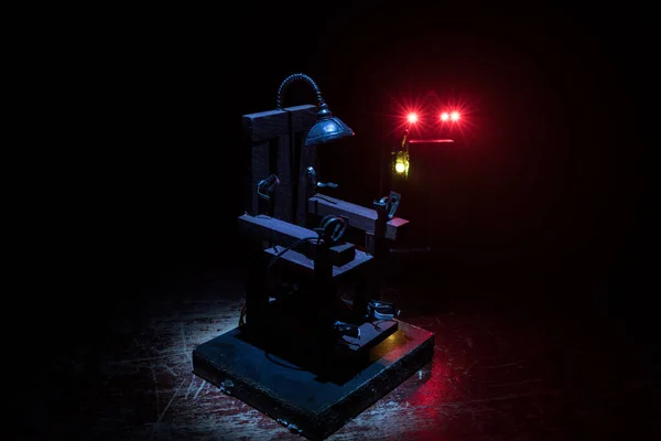 Death penalty electric chair miniature on dark. Creative artwork decoration. Image of an electric chair scale model on a dark backgorund