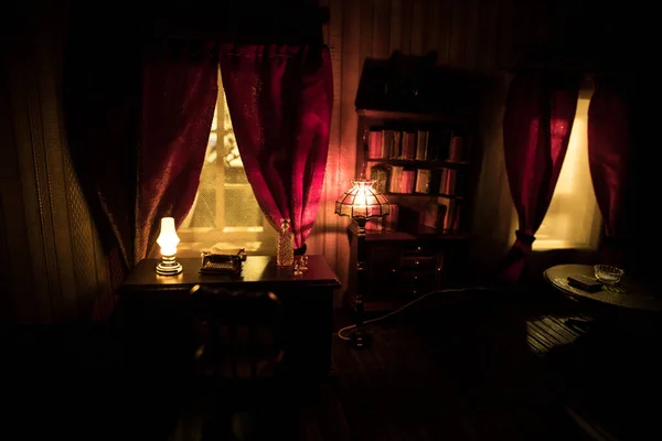 A realistic dollhouse living room with furniture and window at night. Artwork table decoration with handmade realistic dollhouse. Selective focus.