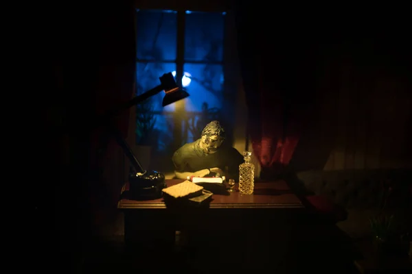 A realistic dollhouse living room with furniture and window at night. Man sitting on table in dark room. Selective focus.