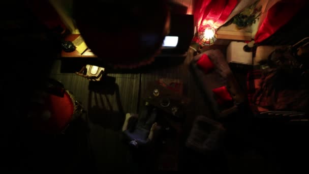 夜には家具や窓のあるリアルな人形の家のリビングルーム 手作りのリアルな人形の家とアートテーブルの装飾 暗い部屋でレトロなスタイルのテレビを着て男 選択的焦点 — ストック動画
