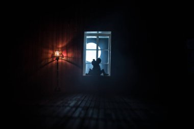 Geceleri mobilyası ve penceresi olan gerçekçi bir bebek evi oturma odası. Pencerede oturan romantik bir çift. El yapımı gerçekçi bebek eviyle sanat masası dekorasyonu. Seçici odak.
