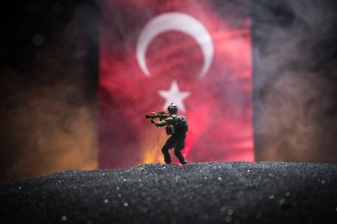 Türk ordusu konsepti. Türk bayrağına karşı silahlı asker silueti. Yaratıcı sanat dekorasyonu. Askeri siluetler dövüş sahnesinde sisli bir arka planda. Seçici odak