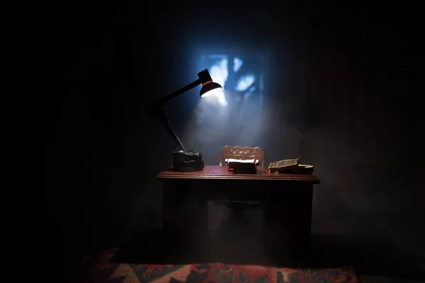 A realistic dollhouse living room with furniture and window at night. Man sitting on table in dark room. Concept of stay home during global virus pandemic. Selective focus.