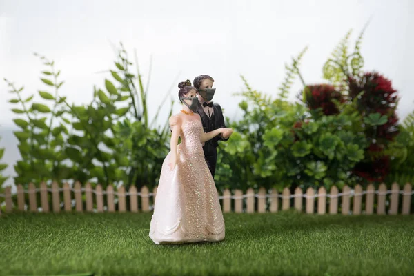 Miniature people : Happy bride wearing masks to protect against viruses during wedding time. People wear masks to prevent New type COVID-19 pneumonia. Coronavirus and Covid-19 concept. Selective focus