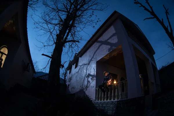 Full moon over quiet village at night. Beautiful night landscape of mountain village under the moonlight. Silhouette of person standing in the dark. Selective focus. Long exposure shot