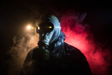 Çevre felaketi. Karanlık bir arka planda gaz maskeli kıyamet sonrası hayatta kalan biri. Gaz maskesi takan bir adamın dramatik portresi. Radyasyon koruması demek. Seçici odak