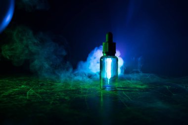 Vape konsepti. Karanlık arka planda duman bulutları ve tüp sıvısı şişeleri. Işık efektleri. Arka plan, vape reklamı ya da vape arkaplan olarak kullanışlı. Seçici odak