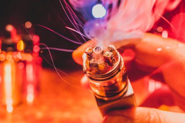 Vape kavramı. Elektronik sigara vape patlama. Duman bulutları ve vape sıvı şişe koyu arka plan üzerinde. Işık efektleri. Vape reklam olarak yararlı. Seçici odak