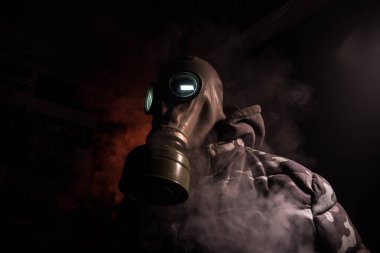 Çevre felaketi. Karanlık bir arka planda gaz maskeli kıyamet sonrası hayatta kalan biri. Gaz maskesi takan bir adamın dramatik portresi. Radyasyon koruması demek. Seçici odak