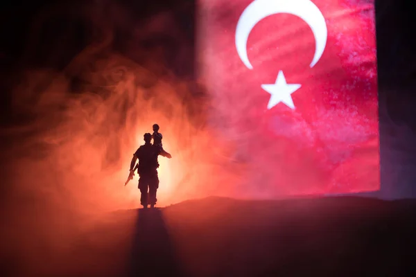 Turkish army concept. Silhouette of soldiers against a Turkish flag. Creative artwork decoration. Turkish soldier carrying little boy on his shoulder. Selective focus