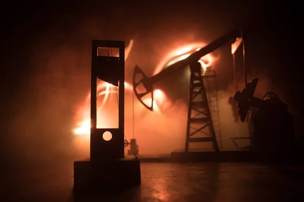 Oil industry crisis concept. Oil stock crisis because Covid global pandemic. Oil pump and oil refining factory at night with fog and backlight. Creative artwork decoration. Selective focus.