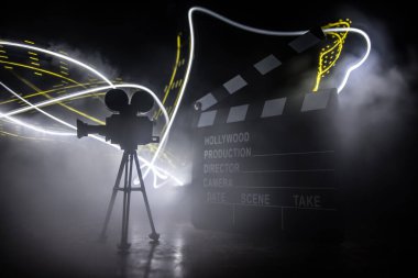 Film konsepti. Sis ve boşluk ile koyu tonlu arkaplanda minyatür film seti. Tripod ve klasördeki klasik kamera silueti. Seçici odak