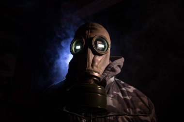 Çevre felaketi. Karanlık bir arka planda gaz maskeli kıyamet sonrası hayatta kalan biri. Gaz maskesi takan bir adamın dramatik portresi. Radyasyon koruması demek. Seçici odak