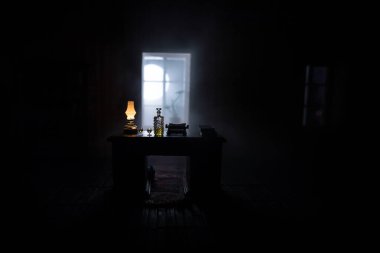 Geceleri mobilyası ve penceresi olan gerçekçi bir bebek evi oturma odası. Karanlık odada masada oturan bir adam. Küresel virüs salgını sırasında evde kalma kavramı. Seçici odak.