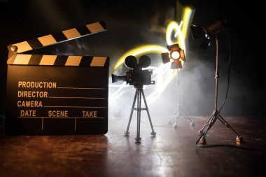 Film konsepti. Sis ve boşluk ile koyu tonlu arkaplanda minyatür film seti. Tripod ve klasördeki klasik kamera silueti. Seçici odak