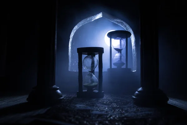 Time concept. A realistic Arabian interior miniature with window and columns. Silhouette of hourglass inside room. Abstract surreal idea with empty space. Selective focus