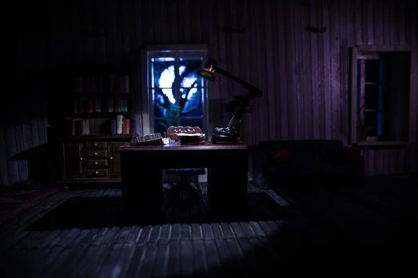 A realistic dollhouse living room with furniture and window at night. Man sitting on table in dark room. Concept of stay home during global virus pandemic. Selective focus.