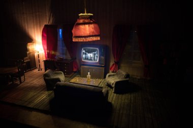 Geceleri mobilyası ve penceresi olan gerçekçi bir bebek evi oturma odası. El yapımı gerçekçi bebek eviyle sanat masası dekorasyonu. Eski usul televizyon. Seçici odak.