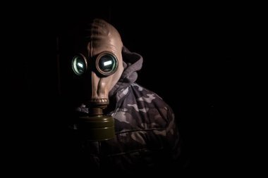 Çevre felaketi. Karanlık bir arka planda gaz maskeli kıyamet sonrası hayatta kalan biri. Gaz maskesi takan bir adamın dramatik portresi. Radyasyon koruması demek. Seçici odak