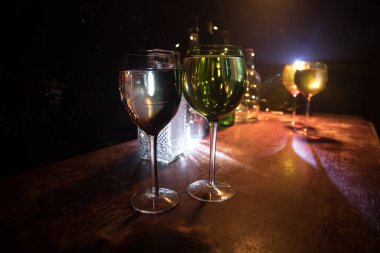 Ahşap masada şarap kadehi ve arka planda güzel renkli ışıklar. Karanlık arka planda şarap kadehleri. Seçici odaklanma. Kulüp içki konsepti