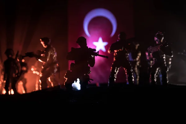 Turkish army concept. Silhouette of armed soldiers against a Turkish flag. Creative artwork decoration. Military silhouettes fighting scene dark toned foggy background. Selective focus