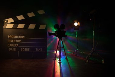 Film konsepti. Sis ve boşluk ile koyu tonlu arkaplanda minyatür film seti. Tripod ve klasördeki klasik kamera silueti. Seçici odak