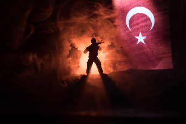 Türk ordusu konsepti. Türk bayrağına karşı silahlı askerlerin silueti. Yaratıcı sanat dekorasyonu. Askeri siluetler dövüş sahnesinde sisli bir arka planda. Seçici odak