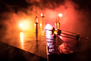 Narcotic drug problem concept. Silhouette of a man standing in the middle of the road on a misty night with giant Drug syringe and narcotic attributes. Creative artwork decoration