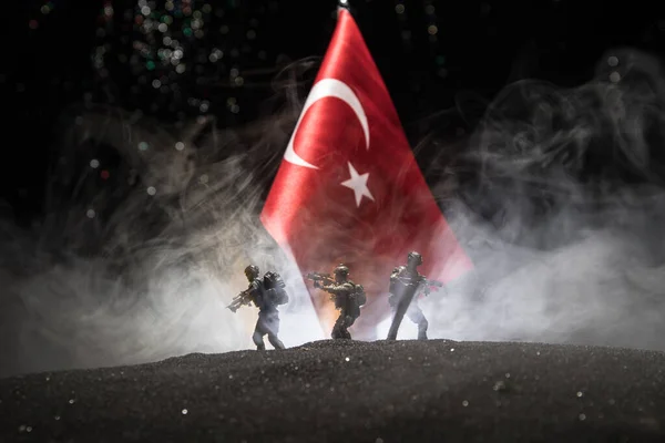 Turkish army concept. Silhouette of armed soldiers against a Turkish flag. Creative artwork decoration. Military silhouettes fighting scene dark toned foggy background. Selective focus