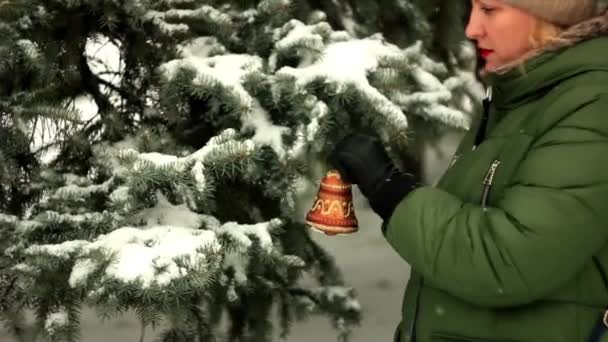 Uma mulher pendura decorações de árvore de Natal — Vídeo de Stock