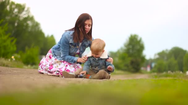Madre e hijo están sentados en la hierba — Vídeos de Stock
