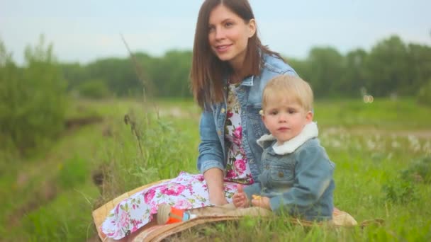 Mère et enfant sont assis sur l'herbe — Video