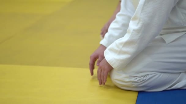 In kimono zittend op de tatami van martial arts. — Stockvideo