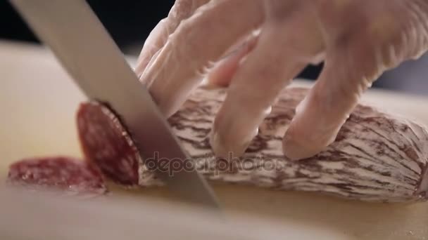 Kocken knivar en salami. Närbild. Manliga händer är knivskurits av en salami. Kapning av en salami kniv närbild — Stockvideo