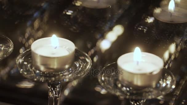 Small candles are displayed in a window. Reflection of candles in a window. The flame of a candle waves on wind. Many small candles cost on a window sill. Holiday divali. Divali — Stock Video