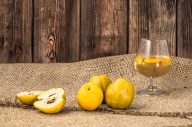 Sweet quince liquor. Glass of drink of tincture on wooden table. clipart