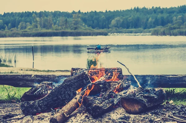 Rustic bonfire by the lake, autumn landscape