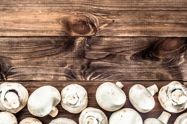 Funghi interi champignons su fondo rustico in legno . — Foto Stock